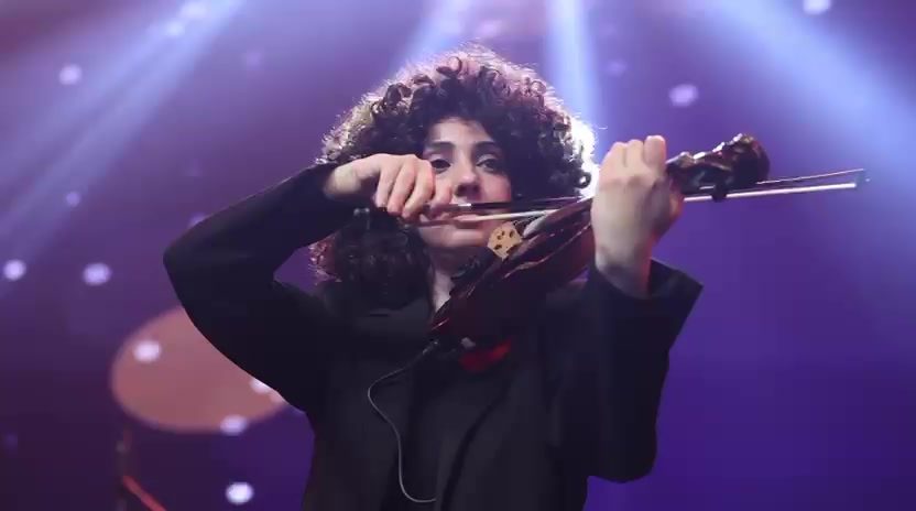 Madina on electric violin under stage lights